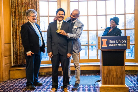 Kevin Jackson places a medal around the neck of Prashant Jain as Jonathan Sweedler and Venetria Patton stand nearby watching. 