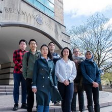 Beckman Institute graduate fellows stand together on steps in front of an entrance to the Beckman Institute.