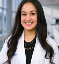 Dr. Melanie Rodriguez in a lab coat in a lab setting in the background