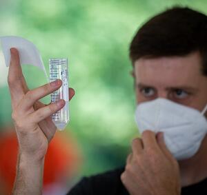 A student looks at a test tube at a COVID-19 testing site on campus