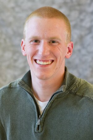 Head shot of graduate student Justin Miller on a gray background