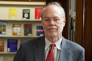 Head shot of Phillip Sharp in a gray suit jacket and red tie in front of book shelves