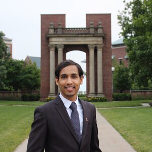 Portrait of Soumitra Athavale standing on a sidewalk in a dark suit and tie