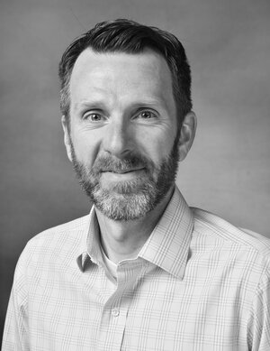 A black and white head shot photo of Alumnus Dennis Livesay.