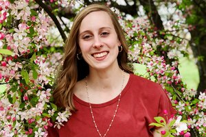 Head shot of Grace Maloney in an outdoor setting with a pink-and-white blooming tree in the background 