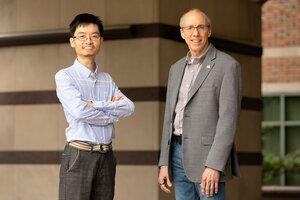 Researchers Yue Liu and Jeffrey Moore stand side by side in front of a concrete wall on campus. 