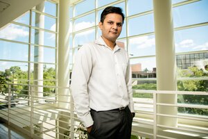 Portrait of Prashant Jain in the second floor atrium of a building with all windows in the background.