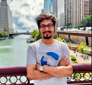 Portrait of Sohang Kundu standing on a bridge over a waterway with a cityscape background