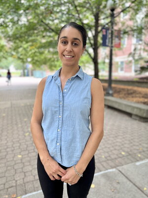 Portrait of Anastasia Manesis standing on a brick walkway lined with trees on the UIUC campus.