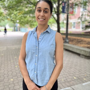 Portrait of Anastasia Manesis standing on a brick walkway lined with trees on the UIUC campus.