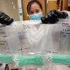 Jia En Aw, a Beckman Institute graduate research assistant and aerospace engineering student, holds 500 swabs being sent for testing