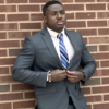 Picture of Samuel Okyem standing and buttoning his suit coat