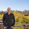Photo of Douglas Mitchell on an outdoor balcony overlooking campus