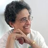 Photo of Lydia Hines seated, smiling, looking away with hands clasped by her face