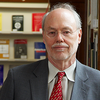 Head shot of Phillip Sharp in a gray suit jacket and red tie in front of book shelves