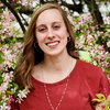 Head shot of Grace Maloney in an outdoor setting with a pink-and-white blooming tree in the background 