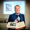 Photo of Greg Girolami standing behind an open book.