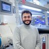 Sagnik Chakrabarti stands in a chemistry lab with equipment in the background
