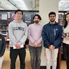 Five of the winners and finalists stand side by side in the library with bookshelves in the background.