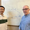 Yunyan Sun and Jeffrey Moore stand in front of a white board with a computational model drawn on the board between them.