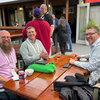 Three event attendees sitting in chairs at a table in an outdoor venue